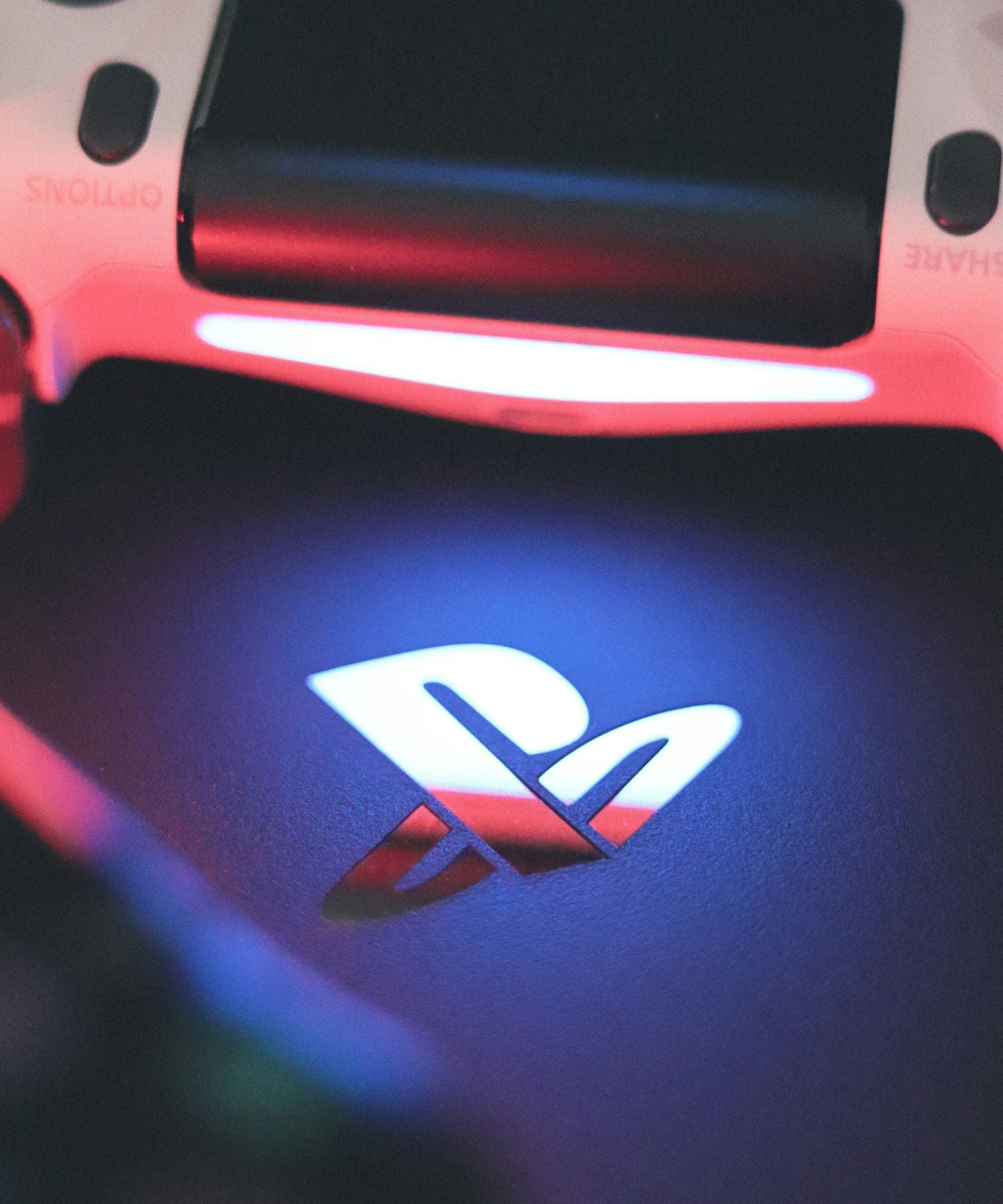 Logo PlayStation éclairer par la lumière rouge d'une manette DualShock 4