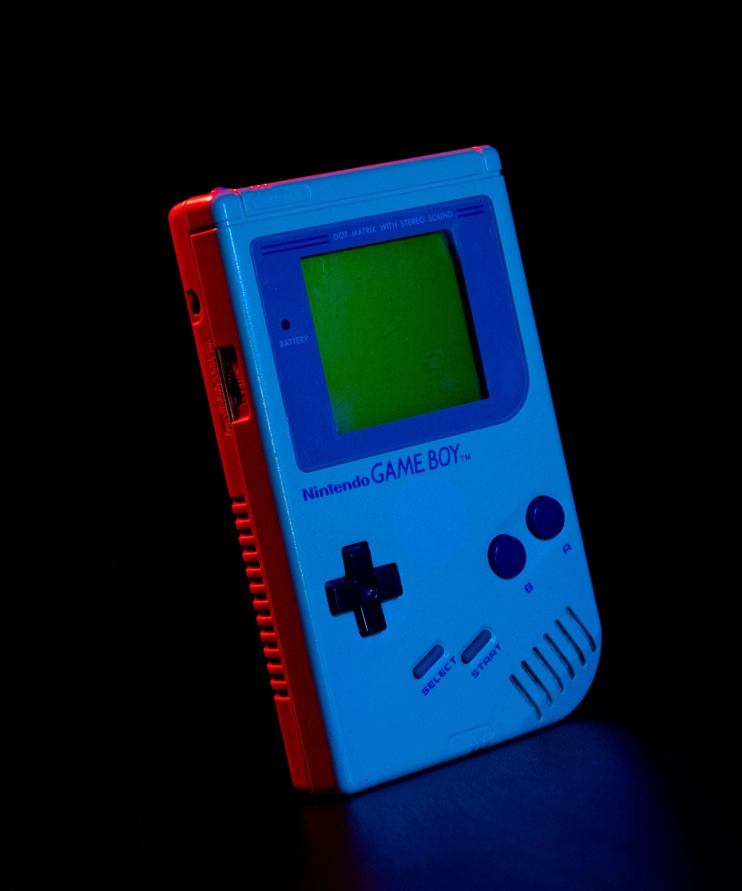 Console Nintendo Game Boy, éclairée par une lumière bleu et une lumière rouge